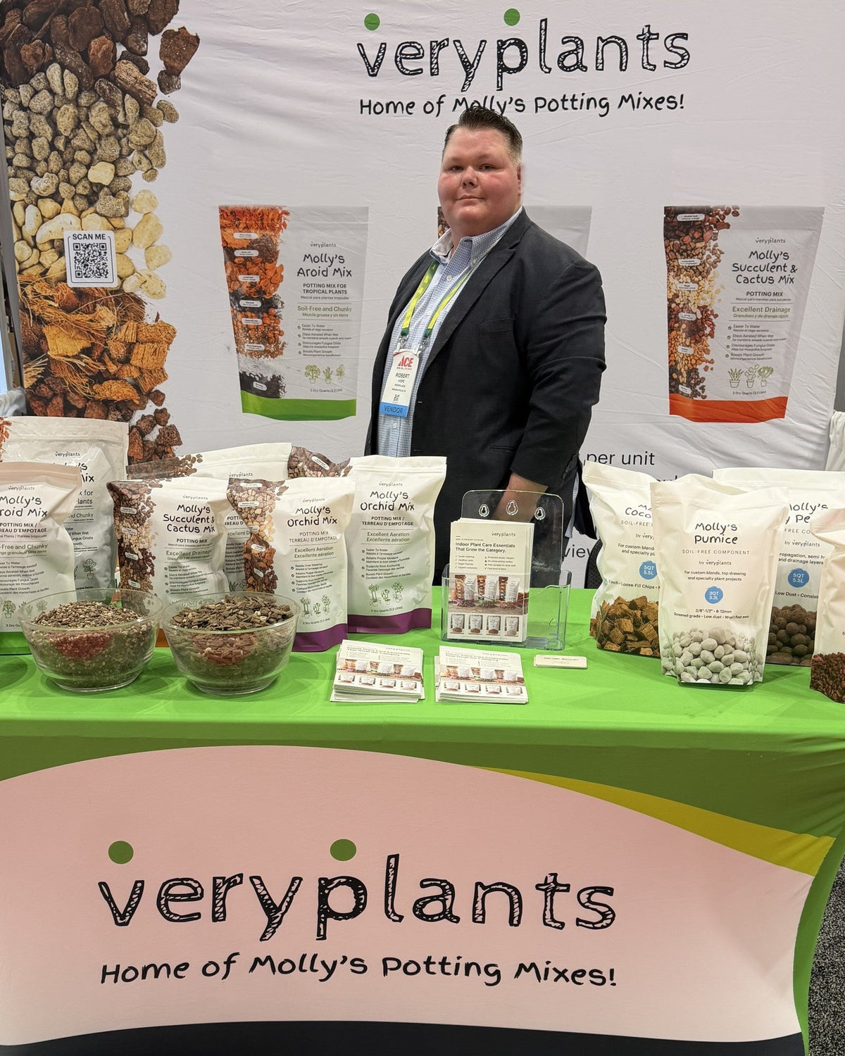 Robert Hope, Director of New Business at Veryplants, at booth 9055 at the Ace Hardware Fall Convention in Orlando, with Molly's Aroid, Succulent, and Orchid mixes and Molly's Components on the table.